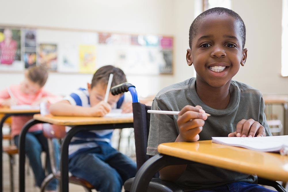 Smiling African American student at his desk in a classroom